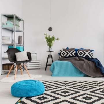 Modern bedroom with large bed and black and white pattern carpet and pillows