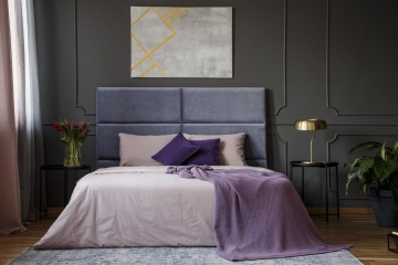 Violet blanket on the bed in pastel bedroom interior with grey poster on grey wall with molding