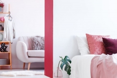 Black clock above bed in bedroom interior with sofa and pink wall in the dressing room